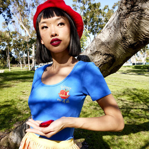 Woman wearing the blue Stitch Shoppe Snow White Kelly Top with a yellow skirt, leaning against a tree